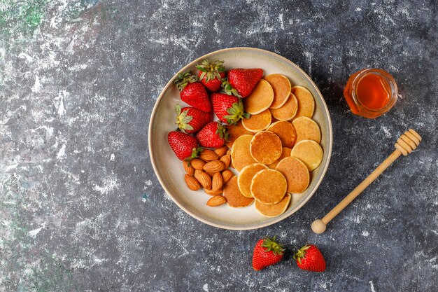 Comida de moda: mini cereal para panqueques. Montón de panqueques de cereales con bayas y nueces.