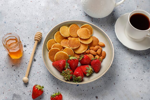 Comida de moda: mini cereal para panqueques. Montón de panqueques de cereales con bayas y nueces.