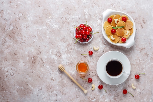 Comida de moda: mini cereal para panqueques. Montón de panqueques de cereales con bayas y nueces.