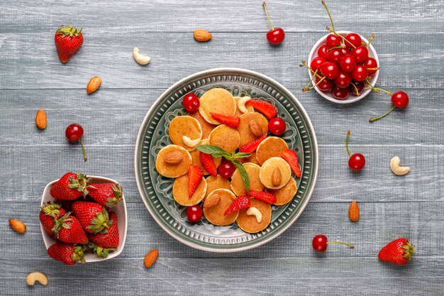 Comida de moda: mini cereal para panqueques. Montón de panqueques de cereales con bayas y nueces.