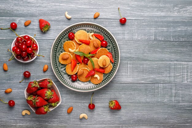 Comida de moda: mini cereal para panqueques. Montón de panqueques de cereales con bayas y nueces.