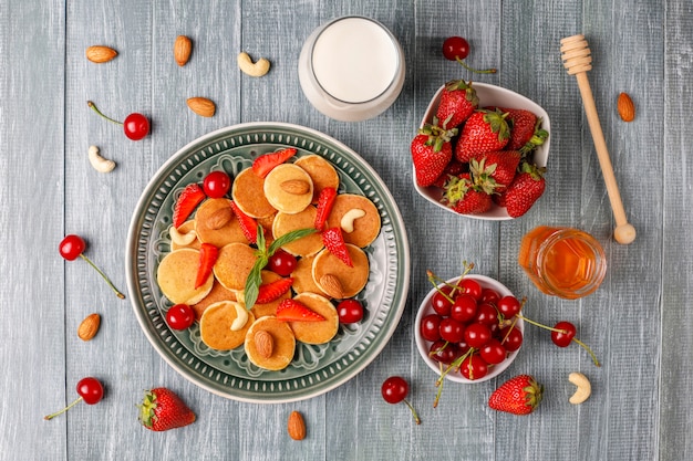 Comida de moda: mini cereal para panqueques. Montón de panqueques de cereales con bayas y nueces.