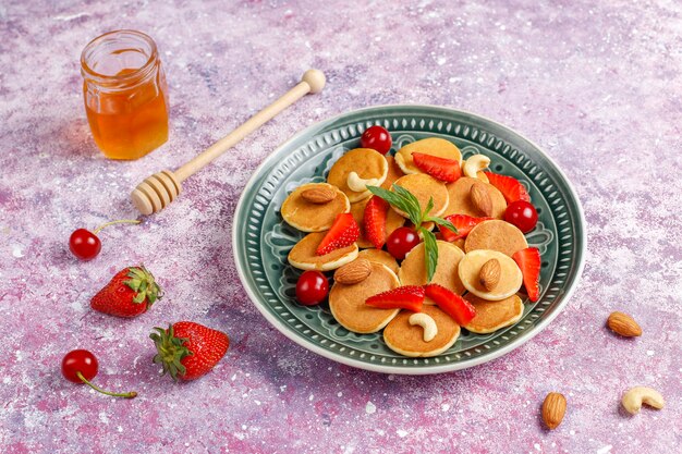 Comida de moda: mini cereal para panqueques. Montón de panqueques de cereales con bayas y nueces.