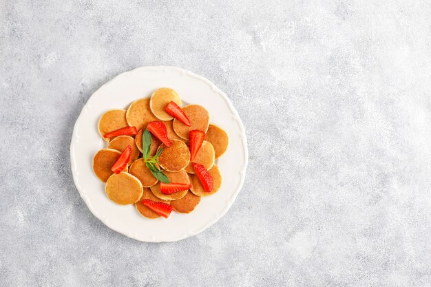 Comida de moda: mini cereal para panqueques. Montón de panqueques de cereales con bayas y nueces.