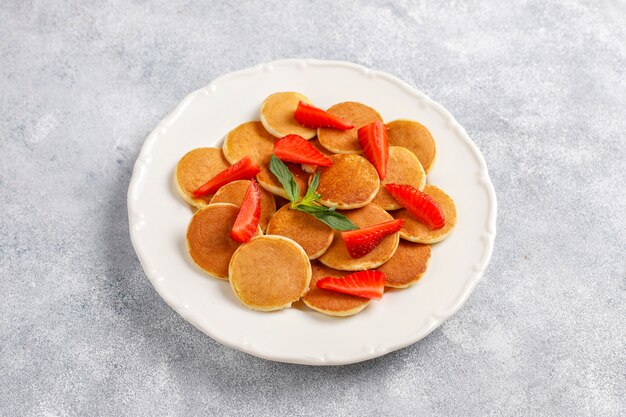 Comida de moda: mini cereal para panqueques. Montón de panqueques de cereales con bayas