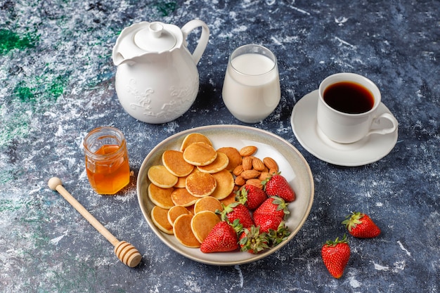 Comida de moda: mini cereal para panqueques. Montón de panqueques de cereales con bayas