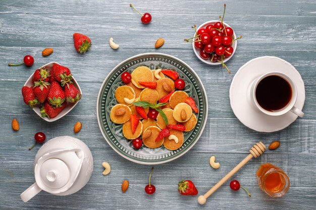 Comida de moda: mini cereal para panqueques. Montón de panqueques de cereales con bayas