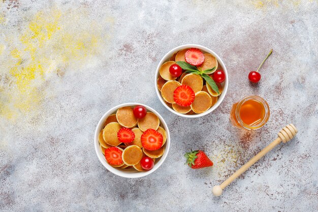 Comida de moda: mini cereal para panqueques. Montón de panqueques de cereales con bayas