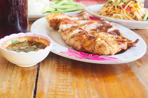 Comida picante al estilo tailandés, pollo a la parrilla con ensalada de papaya picante y bebida fría