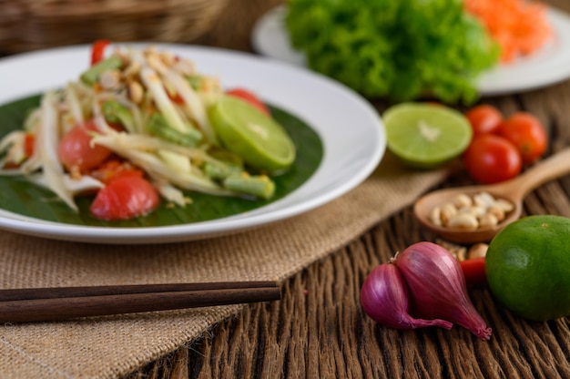 Comida picante de estilo tailandés, concepto de comida Som Tum, decoración de accesorios Ajo, limón, maní, tomate y chalotes en la mesa de madera