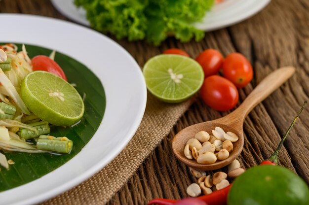 Comida picante de estilo tailandés, concepto de comida Som Tum, decoración de accesorios Ajo, limón, maní, tomate y chalotes en la mesa de madera