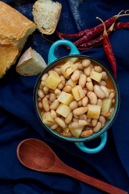 Comida plana con frijoles, patatas y pan.