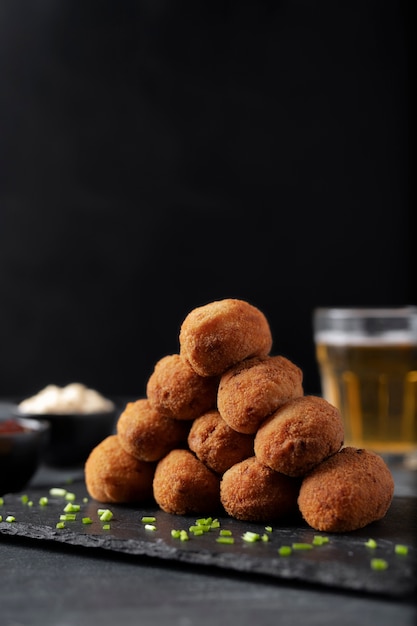 Comida que contiene croquetas con perejil y un vaso de cerveza