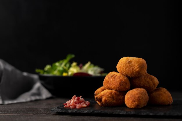 Comida que contiene croquetas con tocino y ensalada