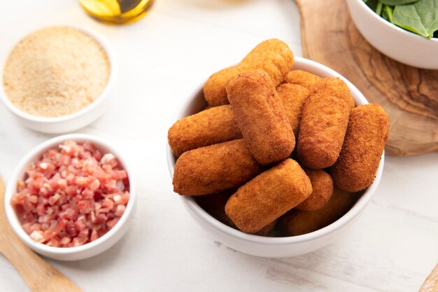 Comida que contiene croquetas con tocino y espinacas