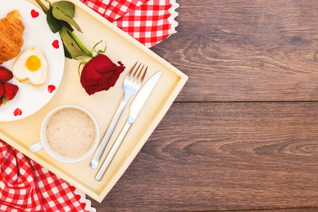 Comida romántica en bandeja con rosa roja