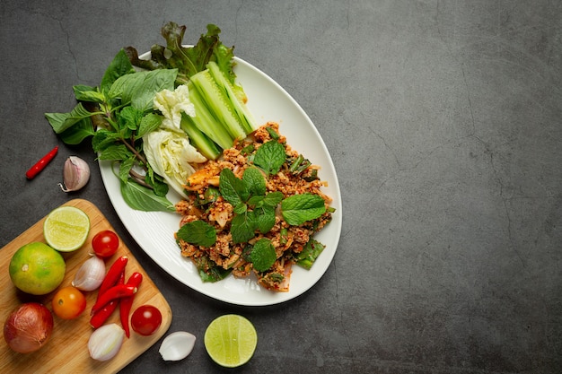 Comida tailandesa; carne de cerdo picada picante servida con guarniciones