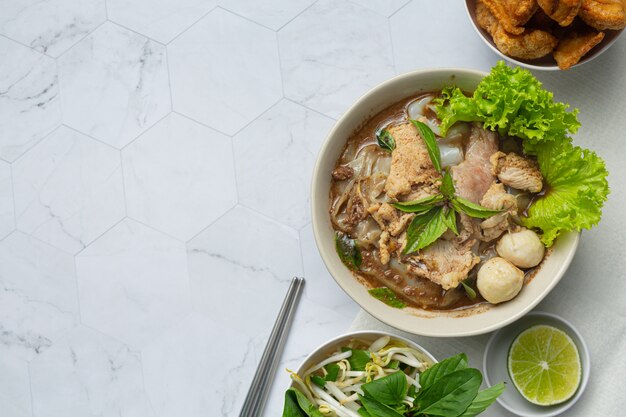 Comida tailandesa. Fideos con cerdo, albóndigas y verdura