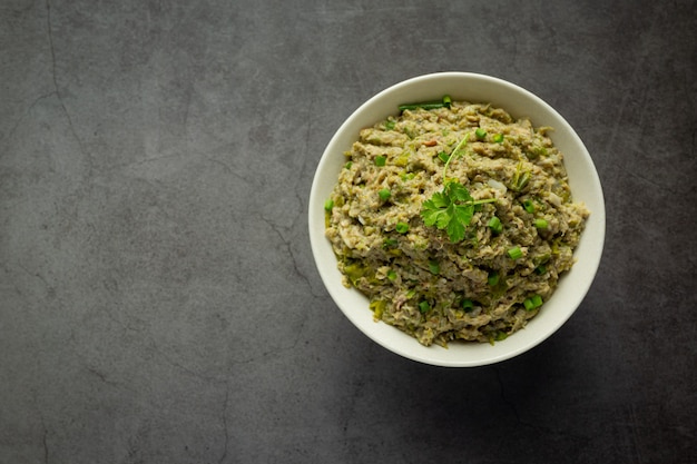 Comida tailandesa; Pasta de ají de caballa en un tazón blanco en lugar oscuro sobre el piso