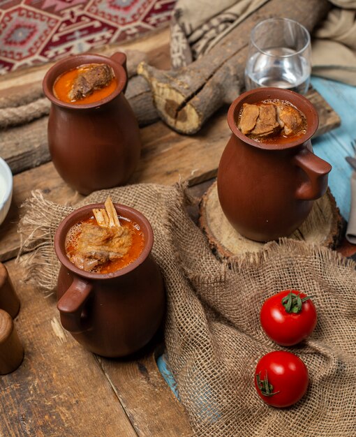 Comida tradicional azerbaiyana piti en tazas de cerámica servida con tomates.