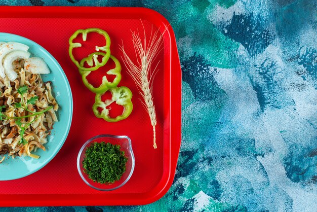 Comida para uno con verduras en rodajas en la bandeja, en la mesa azul.