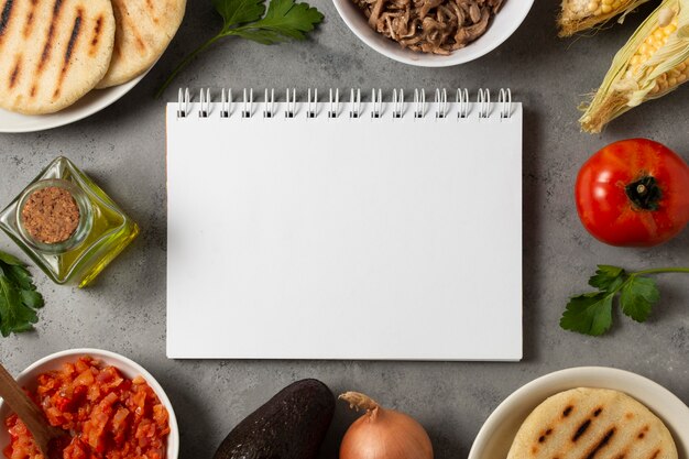 Comida de vista superior con cuaderno vacío