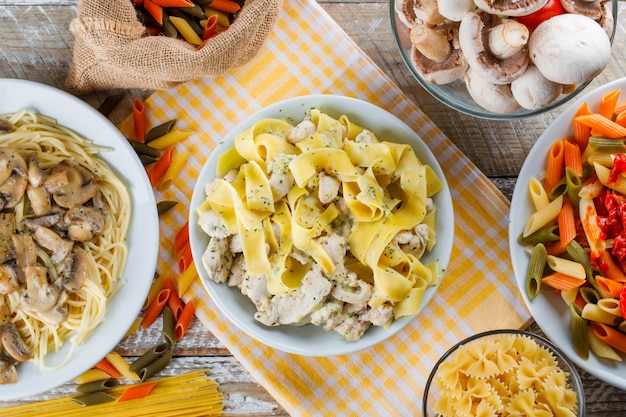 Comidas de pasta en platos con pasta cruda, champiñones