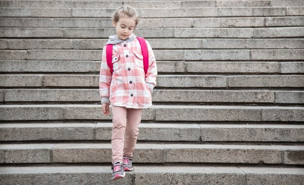 El comienzo de las lecciones y el primer día de otoño. Una dulce niña se encuentra en el contexto de una gran escalera ancha.