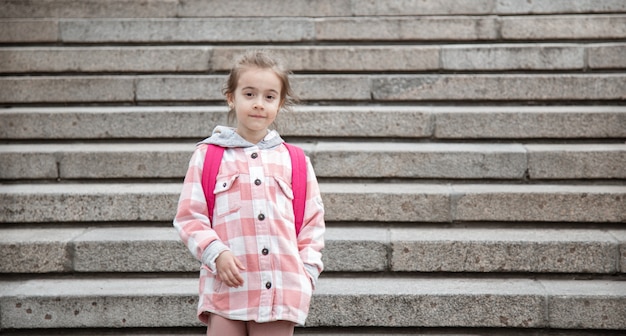 El comienzo de las lecciones y el primer día de otoño. Una dulce niña está de pie contra una gran escalera ancha.