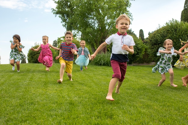Comienzos divertidos. Concepto de moda infantil. El grupo de chicos y chicas adolescentes corriendo en el parque.