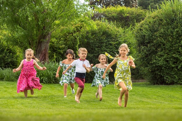 Comienzos divertidos. Concepto de moda infantil. grupo de niños y niñas adolescentes corriendo en el parque