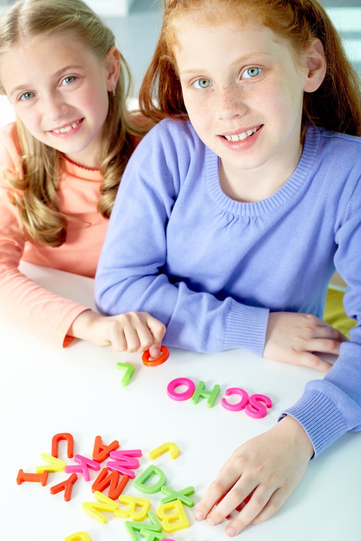 Foto gratuito compañeras de clase jugando con letras de colores