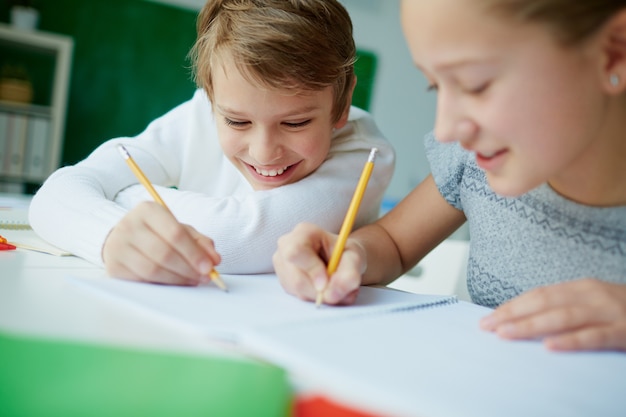 Compañeros de clase escribiendo en el mismo cuaderno