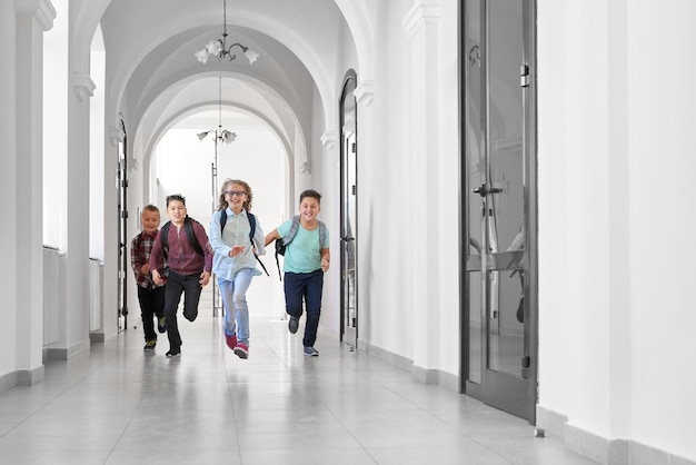 Compañeros de clase felices corriendo en la escuela después de las lecciones