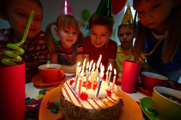 Compañeros de clase mirando la tarta de cumpleaños con velas