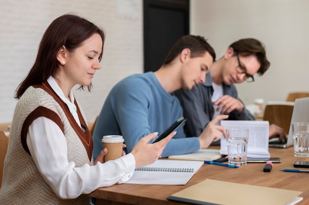 Foto gratuita compañeros de clase con smartphone durante el estudio en grupo