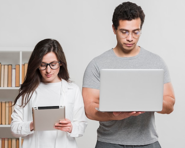 Compañeros de clase universitarios con tableta digital y computadora portátil