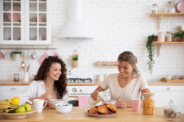 Compañeros de cuarto sonriente desayunando tiro medio