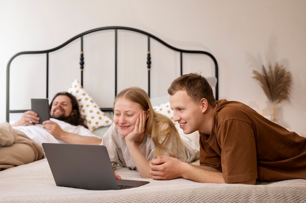 Compañeros de cuarto sonrientes acostados en la cama tiro medio