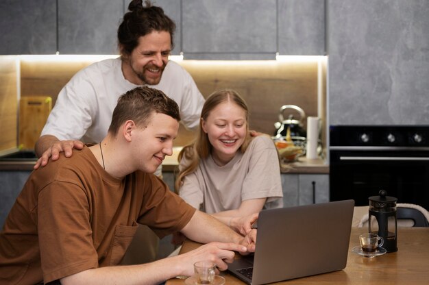 Compañeros de cuarto sonrientes de tiro medio en la cocina con computadora portátil