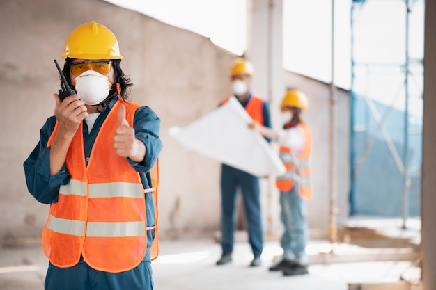 Foto gratuita compañeros con equipo de seguridad que trabajan con planos