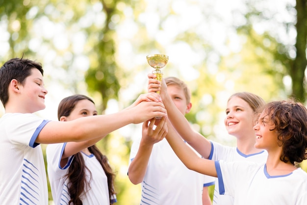 Compañeros de equipo sosteniendo un trofeo de oro