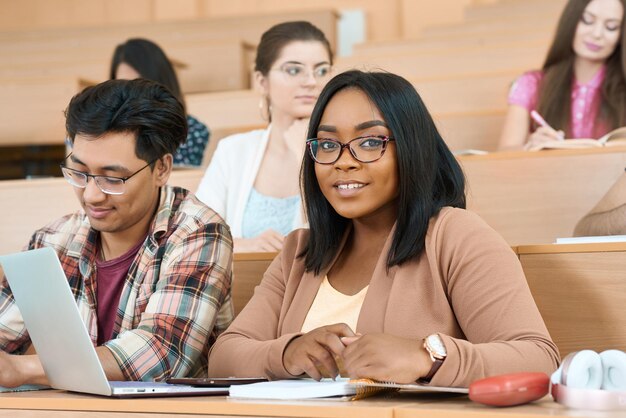 Compañeros de grupo aprendiendo en la universidad chica mirando a la cámara