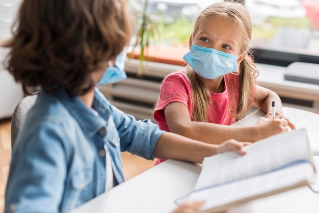 Compañeros haciendo sus deberes mientras usan una máscara médica