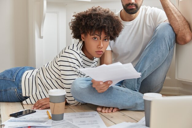 Compañeros masculinos y femeninos multiétnicos de negocios piensan sobre el informe financiero