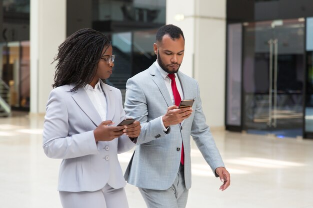 Compañeros de negocios diversos confiados que consultan internet