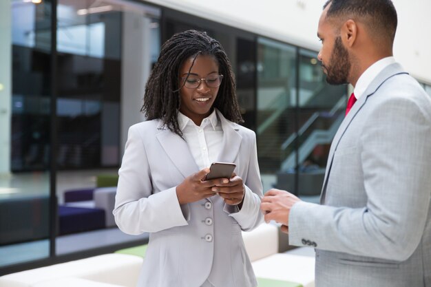 Compañeros de negocios positivos que usan teléfonos móviles