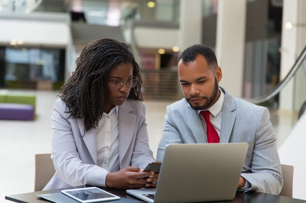 Compañeros de negocios serios que usan gadgets