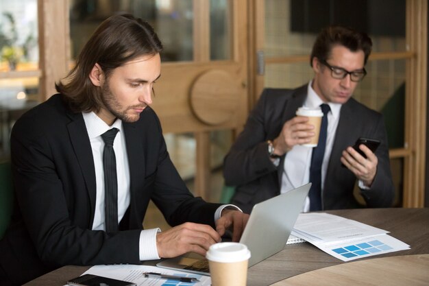 Compañeros ocupados utilizando dispositivos tecnológicos durante el descanso de la empresa