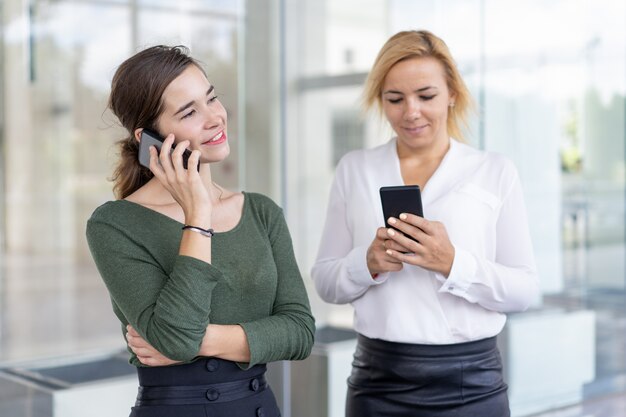 Compañeros de la oficina de contenido utilizando teléfonos